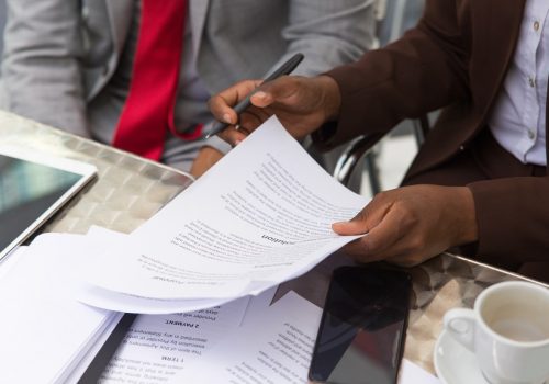 Businessman consulting legal expert in coffee shop. Closeup of business man and woman sitting in cafe and reading documents. Paperwork concept